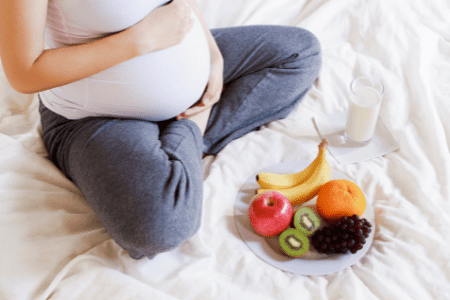 visibly pregnant woman with a plate of mixed fruit fresh fruits
